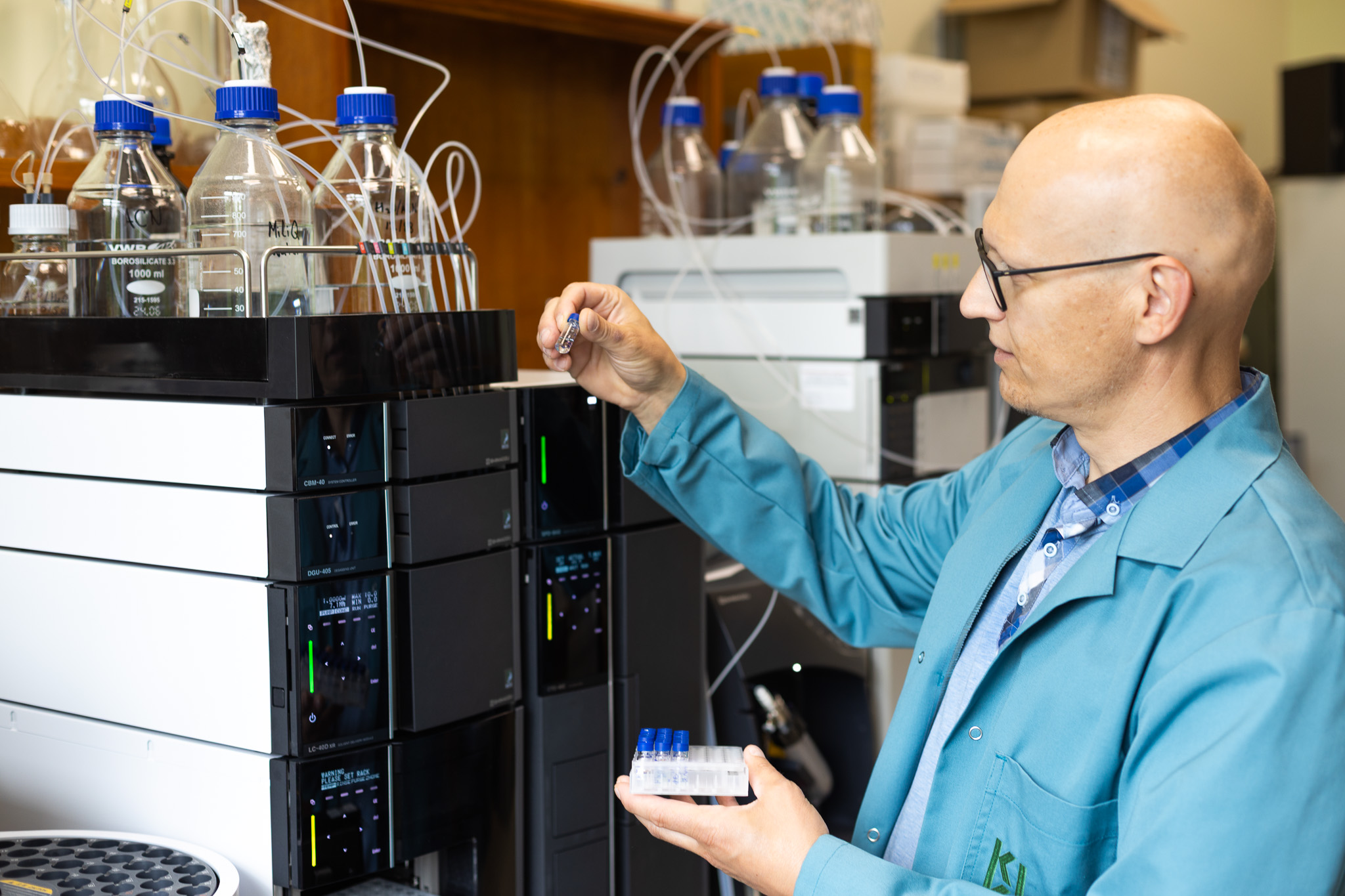 Biorafinēšanas laboratorijas vadošais pētnieks Māris Puķe, rādot vienu no HPLC sistēmai paredzētajiem paraugiem.